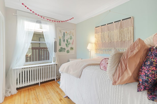 bedroom with radiator heating unit, ornamental molding, and wood-type flooring