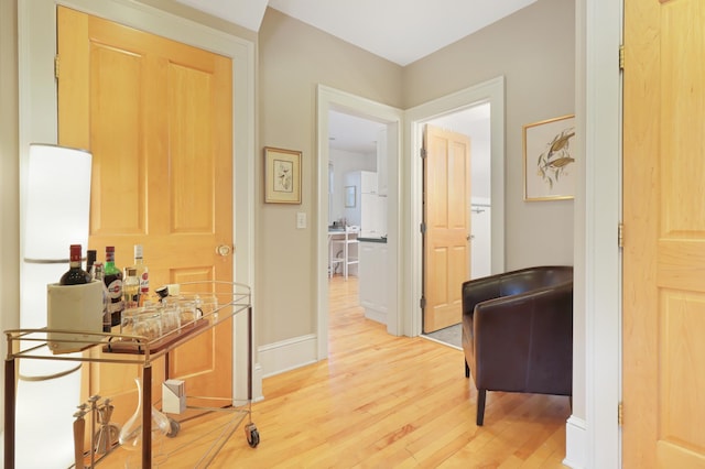 corridor with baseboards and light wood-style floors