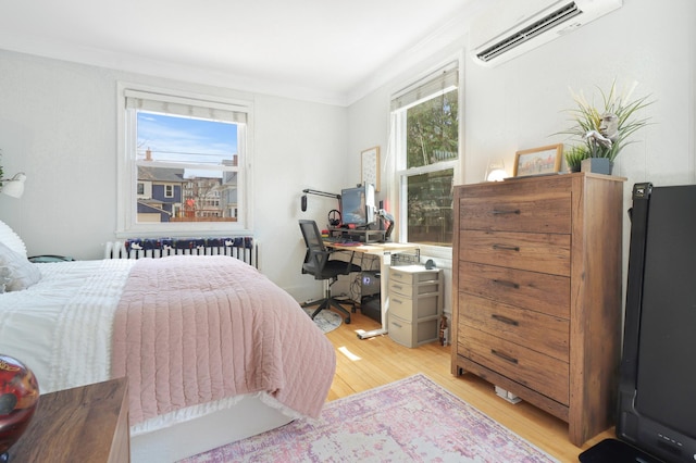 bedroom featuring radiator, light wood finished floors, a wall unit AC, and ornamental molding