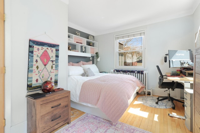 bedroom with radiator, wood finished floors, and ornamental molding