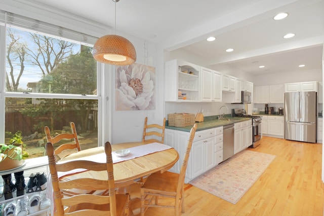 kitchen featuring light wood finished floors, dark countertops, white cabinetry, and appliances with stainless steel finishes