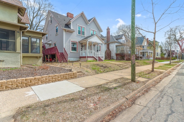view of front of home with stairway, a sunroom, covered porch, and a residential view