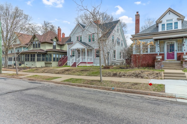 view of front of house with a porch, a chimney, and stairs