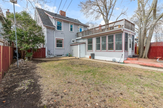 rear view of house featuring a sunroom, a patio, a fenced backyard, and a lawn