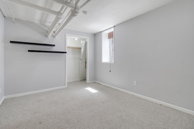 unfurnished bedroom featuring baseboards, carpet, a textured ceiling, and a closet