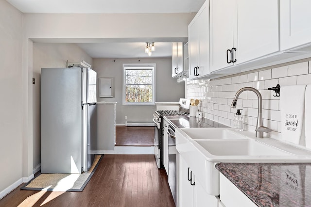 kitchen with white cabinets, a sink, dark wood finished floors, appliances with stainless steel finishes, and backsplash