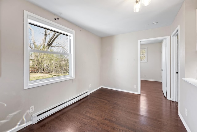 empty room featuring baseboards, baseboard heating, and wood finished floors