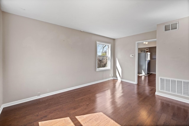 spare room featuring baseboards, wood finished floors, and visible vents
