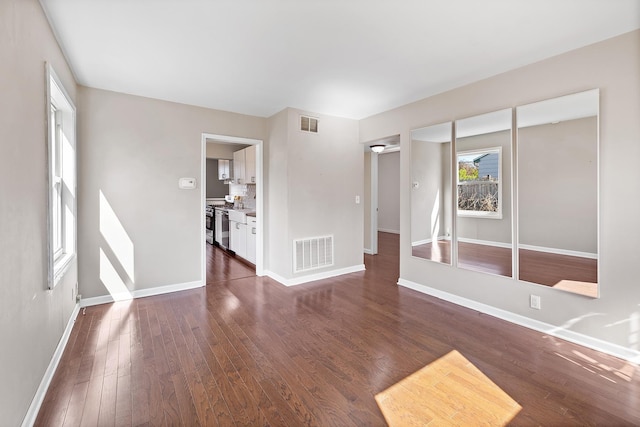 unfurnished living room with visible vents, baseboards, and dark wood-type flooring