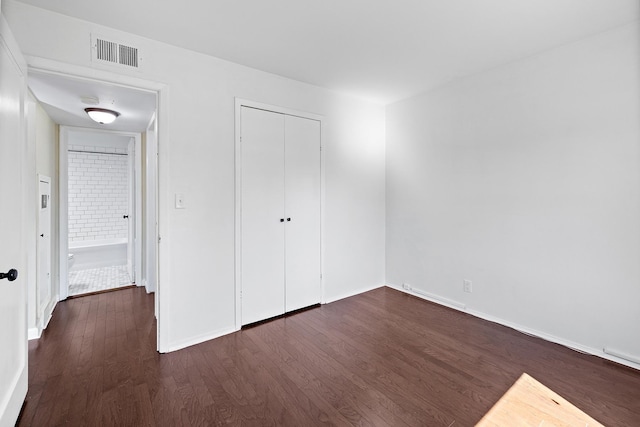 unfurnished bedroom with visible vents, dark wood-style flooring, baseboards, and a closet