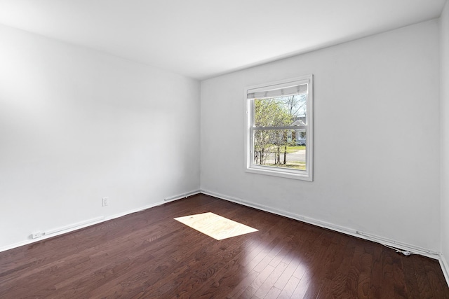 spare room featuring baseboards and dark wood-style floors