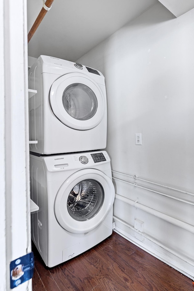 clothes washing area with stacked washer and clothes dryer, wood finished floors, and laundry area