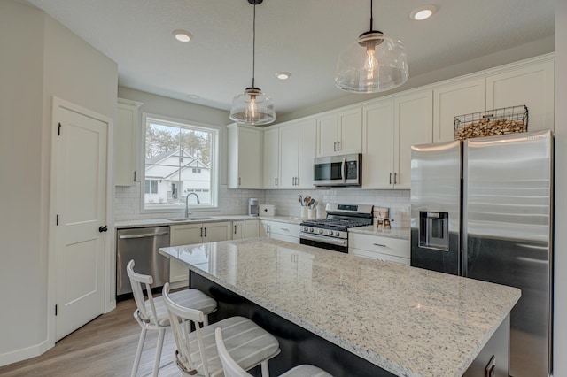 11422 34th St N, Lake Elmo, MN 55042 - kitchen with appliances with stainless steel finishes, a sink, decorative backsplash, light wood-style flooring, and light stone countertops