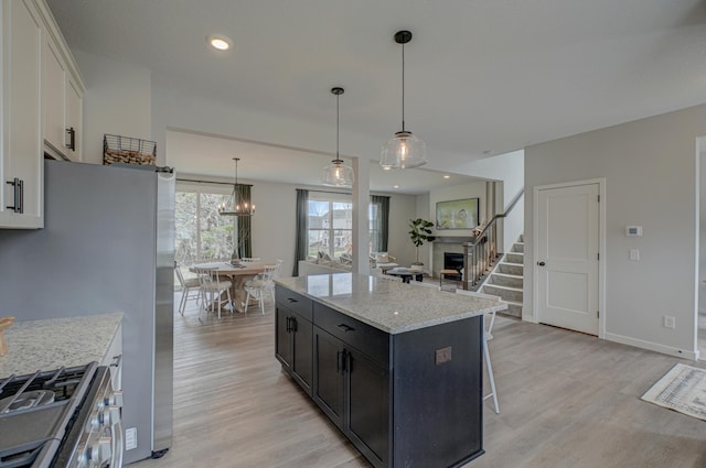 11422 34th St N, Lake Elmo, MN 55042 - kitchen with stainless steel appliances, light wood-style flooring, a kitchen island, white cabinetry, and dark cabinetry
