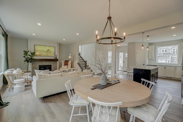 11422 34th St N, Lake Elmo, MN 55042 - dining space with a glass covered fireplace, light wood-type flooring, stairway, a chandelier, and recessed lighting