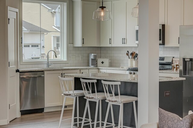 11422 34th St N, Lake Elmo, MN 55042 - kitchen with appliances with stainless steel finishes, a sink, a breakfast bar, light wood-type flooring, and decorative backsplash