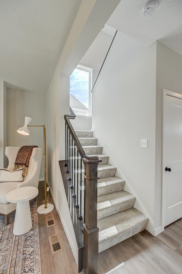 11422 34th St N, Lake Elmo, MN 55042 - stairs featuring wood finished floors, a textured ceiling, and baseboards