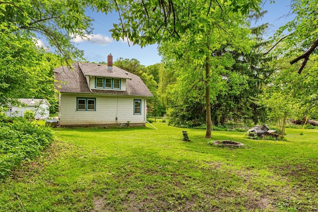 32673 Rosewood Ln, Saint Peter, MN 56082 - rear view of property featuring an outdoor fire pit, a chimney, a lawn, and roof with shingles