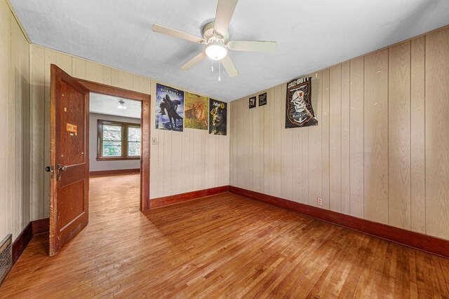32673 Rosewood Ln, Saint Peter, MN 56082 - spare room featuring hardwood / wood-style flooring, ceiling fan, wooden walls, and baseboards
