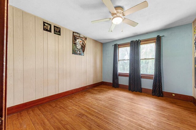 32673 Rosewood Ln, Saint Peter, MN 56082 - spare room featuring wood-type flooring, baseboards, a ceiling fan, and wood walls