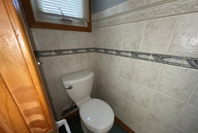 bathroom with toilet and tile walls