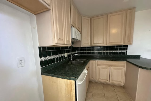kitchen with white appliances, backsplash, light tile patterned flooring, dark countertops, and a sink