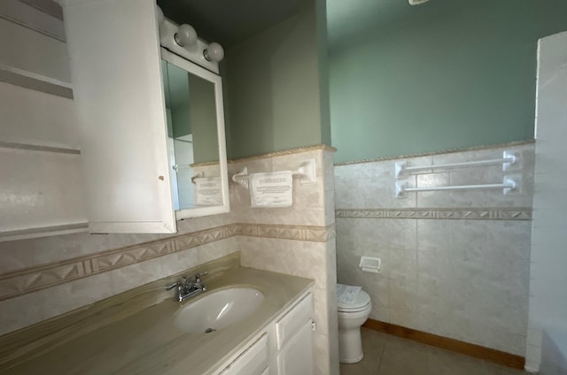 full bath with toilet, tile walls, a wainscoted wall, vanity, and tile patterned floors