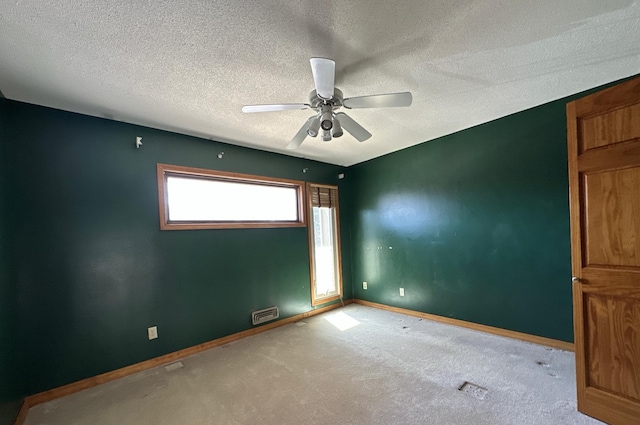spare room featuring carpet, a textured ceiling, a ceiling fan, visible vents, and baseboards