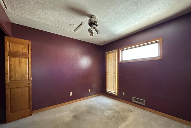 unfurnished room with carpet, visible vents, baseboards, and a textured ceiling