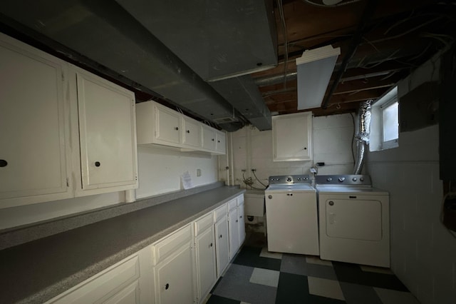 clothes washing area with washing machine and dryer, dark floors, and cabinet space