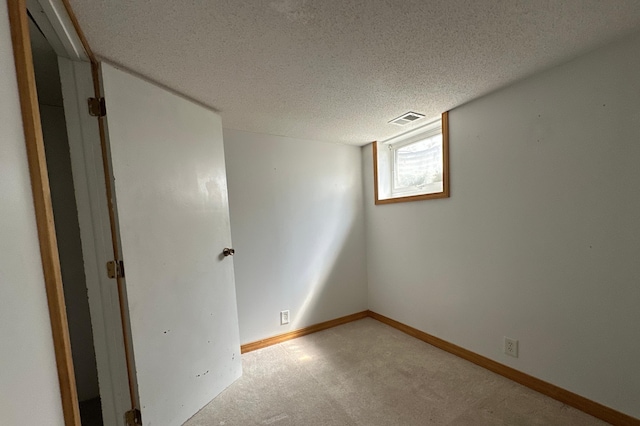 unfurnished room with visible vents, baseboards, light carpet, and a textured ceiling