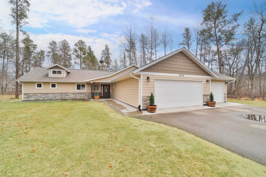 13772 Oakwood Dr, Baxter, MN 56425 - view of front of property with an attached garage, aphalt driveway, stone siding, and a front lawn