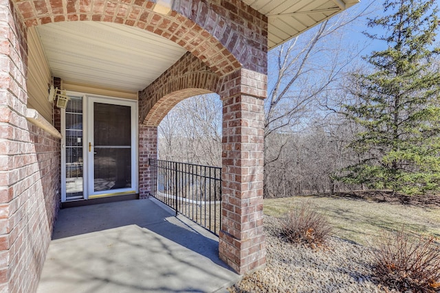 view of exterior entry featuring brick siding and a balcony