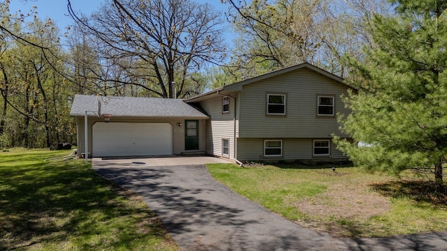 split level home with a garage, asphalt driveway, and a front yard