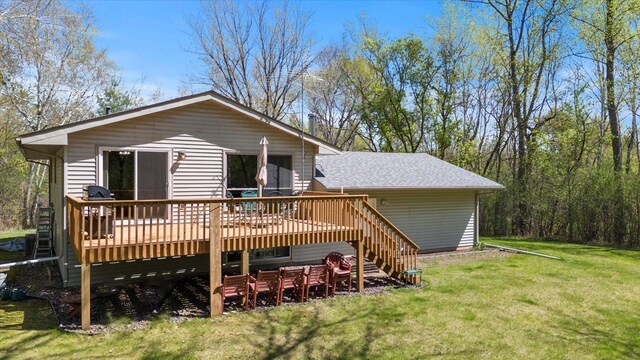 rear view of property with a deck, a yard, stairs, and roof with shingles