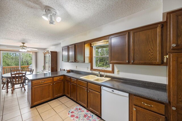 kitchen featuring white dishwasher, a peninsula, a sink, plenty of natural light, and a textured ceiling