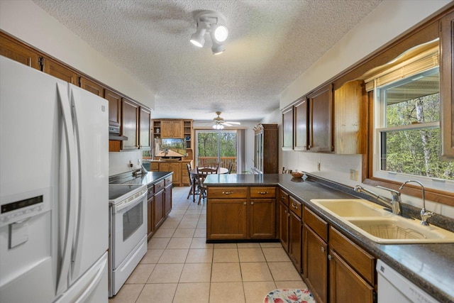 kitchen featuring white appliances, a textured ceiling, a sink, a peninsula, and dark countertops