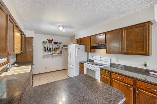 kitchen featuring white appliances, ventilation hood, a sink, dark countertops, and light tile patterned floors