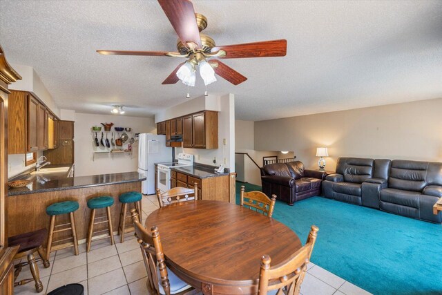 dining space with light tile patterned floors, ceiling fan, a textured ceiling, and light carpet