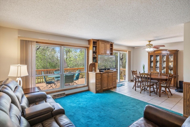 living room with light tile patterned flooring, a textured ceiling, and a ceiling fan