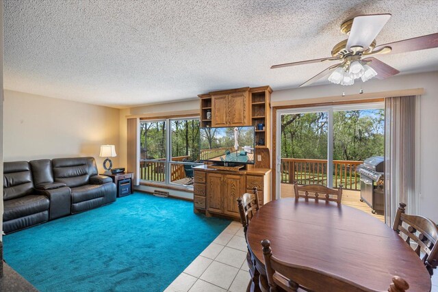 living room with ceiling fan, light tile patterned floors, and a textured ceiling
