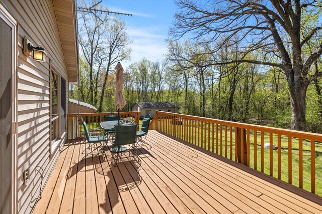 wooden deck with outdoor dining space, a yard, and an outbuilding