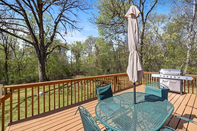 deck with area for grilling, outdoor dining space, and a yard