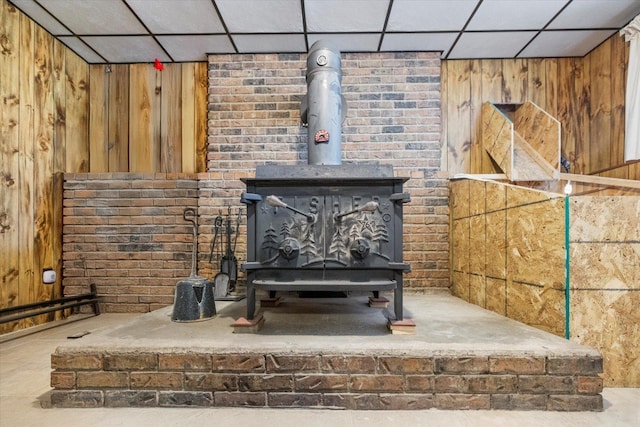 detailed view of a paneled ceiling, wood walls, and a wood stove