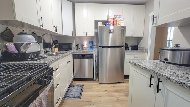 1023 17th Ave SE, Minneapolis, MN 55414 - kitchen featuring stainless steel appliances, light wood-style floors, white cabinetry, and light stone countertops