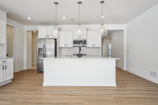 kitchen with white cabinets, tasteful backsplash, stainless steel appliances, and visible vents