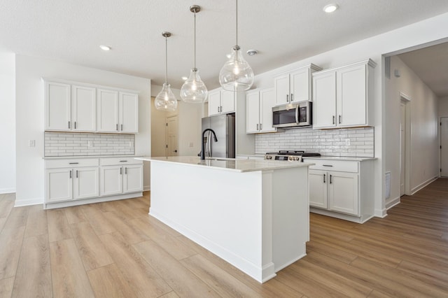 kitchen featuring tasteful backsplash, light wood-type flooring, light countertops, white cabinets, and appliances with stainless steel finishes
