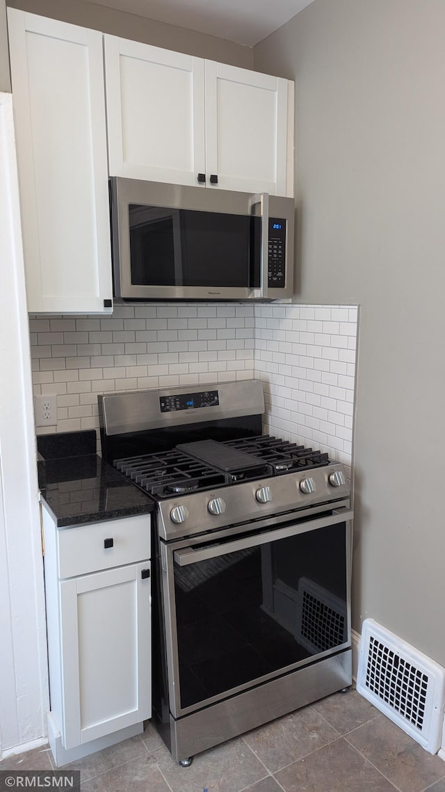 3454 Newton Ave N, Minneapolis, MN 55412 - kitchen featuring appliances with stainless steel finishes, white cabinetry, tasteful backsplash, and dark stone countertops