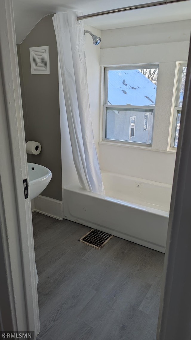 3454 Newton Ave N, Minneapolis, MN 55412 - bathroom featuring wood finished floors, baseboards, shower / bathtub combination with curtain, and lofted ceiling