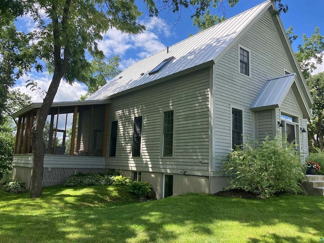 view of home's exterior with a yard, a sunroom, and metal roof